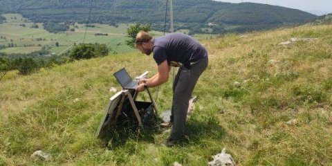 An ecologist setting up equipment in grassland near the wind farm