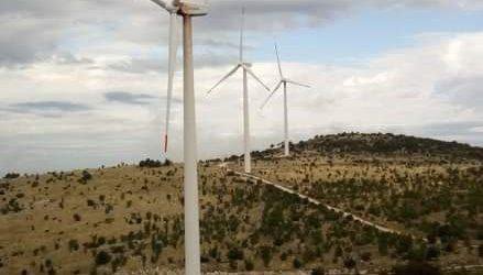Three wind turbines on a dry karst ridge under a cloudy sky